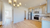 Located on Alfalfa Drive in Carlisle, Pennsylvania, this three-story home offers four bedrooms, two bathrooms, and a thoughtfully designed layout spread across multiple levels. The ground floor features an attached garage with a concrete floor, automatic opener, and built-in shelving, along with entry hallway access via a carpeted staircase with a classic wood banister.

The main living level is the heart of the home, showcasing light hardwood-style flooring throughout. The kitchen is well-equipped with gray shaker-style cabinetry, granite countertops, and a full suite of stainless steel appliances including a refrigerator, electric range, microwave, and dishwasher. A stylish chandelier illuminates the open dining area, and a glass door leads to an outdoor balcony, filling the space with natural light. An adjacent walk-in pantry adds practical storage.

The bedrooms are bright and comfortable, with several featuring ceiling fans, plush carpeting, and generous closet space. The primary bedroom includes a walk-in closet. The bathrooms are clean and functional, featuring a walk-in shower with a white surround. Throughout the home, neutral tones, white trim, and abundant natural light from multiple windows create a fresh, welcoming atmosphere.
