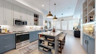 Located in Scottsdale, Arizona, this well-appointed one-bedroom, one-bathroom residence offers a thoughtfully designed single-floor layout with modern finishes throughout. The open-concept kitchen and living area serves as the heart of the home, where two-tone cabinetry in soft gray and blue pairs with granite countertops, a classic white subway tile backsplash, and a full suite of stainless steel appliances. A central island with built-in shelving and seating provides both functionality and a natural gathering point, illuminated by striking brass pendant lights overhead. Light wood flooring runs throughout the main living area, complementing the bright, neutral palette. The living room benefits from large windows with plantation shutters that invite abundant natural light, creating an airy and welcoming atmosphere. A sputnik-style chandelier adds a contemporary design accent overhead. The bedroom is carpeted for comfort, features multiple windows with warm drapery, and offers a cozy, well-proportioned retreat. The bathroom is elegantly finished with large-format gray tile flooring, a marble-topped vanity with under-mount sink, backlit mirrors, and a glass-enclosed walk-in shower. A dedicated closet and hallway complete this efficient and polished Scottsdale residence.