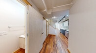 Located at 4611 South Ellis Avenue in Chicago's vibrant South Side, this two-floor residence offers a well-considered layout across two generously proportioned levels. Rich, warm-toned hardwood flooring flows consistently throughout both floors, creating a cohesive and inviting atmosphere from room to room.

The main level houses an open kitchen and living area, where the galley-style kitchen stands out with sleek two-tone cabinetry — pairing light upper cabinets with dark lower units — complemented by a mosaic tile backsplash, white countertops, stainless steel appliances, and track lighting overhead. The adjacent living area is bright and open, with clean white walls and ample room to configure a comfortable living space.

A hallway on the upper level connects the bedroom and bathrooms, maintaining a clean and functional flow. The bedroom is a well-sized, private retreat with a window allowing natural light. The three bathrooms are finished to a modern standard: one features a glass-enclosed walk-in shower with subway tile detailing and a pedestal sink, while another offers a full soaking tub with tiled surround and a floating vanity. A third, more compact bathroom provides additional convenience. Throughout, white large-format tiles and recessed lighting lend a clean, contemporary feel.