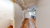 Located at 4611 South Ellis Avenue in Chicago's vibrant South Side, this two-floor residence offers a well-considered layout across two generously proportioned levels. Rich, warm-toned hardwood flooring flows consistently throughout both floors, creating a cohesive and inviting atmosphere from room to room.

The main level houses an open kitchen and living area, where the galley-style kitchen stands out with sleek two-tone cabinetry — pairing light upper cabinets with dark lower units — complemented by a mosaic tile backsplash, white countertops, stainless steel appliances, and track lighting overhead. The adjacent living area is bright and open, with clean white walls and ample room to configure a comfortable living space.

A hallway on the upper level connects the bedroom and bathrooms, maintaining a clean and functional flow. The bedroom is a well-sized, private retreat with a window allowing natural light. The three bathrooms are finished to a modern standard: one features a glass-enclosed walk-in shower with subway tile detailing and a pedestal sink, while another offers a full soaking tub with tiled surround and a floating vanity. A third, more compact bathroom provides additional convenience. Throughout, white large-format tiles and recessed lighting lend a clean, contemporary feel.