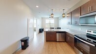 Located at 1222 Patrick Henry Dr in Blacksburg, VA, this one-bedroom, one-bathroom unit offers a well-designed, single-floor layout that makes efficient use of its compact footprint. Light wood-style flooring flows consistently throughout, creating a cohesive and clean aesthetic across all rooms.

The open-concept kitchen serves as the heart of the unit, featuring rich dark and warm-toned cabinetry, granite countertops, and a peninsula with bar seating for two. Stylish pendant lights hang above the island, complementing the stainless steel appliances — including a refrigerator, range, microwave, and dishwasher — to deliver a modern, functional cooking space. Natural light filters in through a window facing the living area, enhancing the open feel.

The bedroom is a comfortably sized retreat, benefiting from a large window with outdoor views of the surrounding greenery and a ceiling fan for added comfort. Neutral walls and wood-style flooring keep the atmosphere calm and versatile.

The full bathroom is well-appointed with a dark-cabinet vanity, granite countertop, a large mirror with dedicated lighting, and a tiled shower-tub combination. A dedicated walk-in closet adjacent to the bedroom offers wire shelving and hanging rods, providing generous storage. The unit's layout and finishes make it a practical and attractive space in Blacksburg.