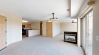This single-floor residence offers a thoughtfully designed open-concept layout that seamlessly connects the living and kitchen areas. The living space is anchored by a glass-front fireplace set into a granite-topped surround, complemented by plush wall-to-wall carpeting and a ceiling fan overhead. A Tiffany-style pendant light fixture adds a decorative touch, illuminating the generous open area.

The kitchen is well-equipped with warm honey-toned wood cabinetry extending to the ceiling, dark granite countertops, black appliances including an electric range and over-the-range microwave, and durable tile flooring. A peninsula with a sink connects the kitchen to the living area, enhancing the open flow.

The bedrooms are carpeted and comfortably sized, each featuring ceiling fans and wood-paneled doors. The primary bedroom includes access to a walk-in closet, providing ample storage. Additional bedrooms feature windows that invite natural light and views of the surrounding neighborhood.

The bathrooms are finished with patterned tile flooring, granite-topped vanities, white cabinetry, and full tub/shower combinations. Neutral warm-toned walls throughout the home create a cohesive and inviting atmosphere, making this a functional and comfortable single-level living space.