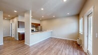 Located at 4040 Hayesville Dr NE in Salem, Oregon, this well-appointed one-bedroom, two-bathroom single-story home offers a thoughtfully designed layout with contemporary finishes throughout. The open-concept kitchen and living area serves as the heart of the home, featuring warm wood-toned cabinetry that extends to the ceiling for generous storage, sleek white quartz countertops, stainless steel appliances including a refrigerator, range, and built-in microwave, and a peninsula with an integrated sink — ideal for both cooking and casual dining. Light wood-look flooring flows through the living and kitchen areas, complementing the neutral wall tones and recessed lighting overhead. A separate entry area with a sliding glass door provides access to the outdoors and allows natural light to fill the space. The bedroom is finished with plush carpeting, a window with outdoor views, and a sliding-door closet with a full-length hanging rod. Two bathrooms serve the home — one featuring a spacious walk-in shower with a framed glass door, and the other equipped with a full soaking tub and shower combination. Clean white walls, brushed nickel hardware, and wood-look flooring carry the home's consistent modern aesthetic into these functional spaces.