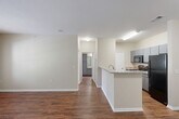 This single-story residence in Chattanooga, Tennessee offers a thoughtfully designed layout that maximizes its comfortable footprint. The open-concept kitchen and living area serve as the heart of the home, with rich hardwood-style flooring flowing throughout. The kitchen is well-equipped with granite-look countertops, a peninsula with a built-in sink, sleek gray cabinetry, and black appliances including a refrigerator and range. The peninsula provides additional workspace while connecting seamlessly to the open living area.

The living room is bright and welcoming, featuring a glass-paneled door and adjacent window that invite generous natural light and provide outdoor views. The space offers a clean, neutral palette with warm beige walls and crisp white trim throughout.

The generously sized primary bedroom is appointed with plush carpeting, a ceiling fan with light fixture, a window with outdoor views, and direct access to both a dedicated walk-in closet and an ensuite bathroom featuring dark cabinetry and ample vanity space.

A dedicated laundry room with wire shelving and washer/dryer hookups adds everyday convenience. The overall ambiance is clean, modern, and move-in ready, making this Chattanooga residence a practical and comfortable place to call home.
