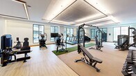 Located in the heart of uptown Charlotte at 426 N Tryon St, this expansive fitness center offers a thoughtfully designed, single-floor layout encompassing a generous amount of workout space across multiple dedicated zones. The facility is introduced by a wide corridor adorned with a striking, large-scale colorful mural that sets a vibrant, energetic tone throughout the space.

The main workout floor features light hardwood-style flooring and is equipped with a comprehensive selection of TRUE-brand cardio machines, including treadmills, ellipticals, and stair climbers, all positioned near floor-to-ceiling windows that flood the area with natural light and offer views of the surrounding cityscape. Turf strips run through the strength training zone, which is outfitted with cable machines, functional trainers, and a variety of benches and free weights.

A separate cycling studio houses a row of indoor spin bikes and benefits from large street-facing windows, creating a bright, open atmosphere. An additional studio space includes portable ballet barres, suitable for stretching, barre, or yoga sessions. Storage closets provide organizational support throughout the facility. Recessed and linear lighting complements the natural light, while the bold mural artwork anchors the reception area, which includes a water station and open shelving. The overall design balances modern aesthetics with high-functionality.