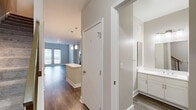 This contemporary two-floor residence offers a well-designed layout with thoughtful finishes throughout. The main living area impresses with soaring double-height ceilings and sleek hardwood-style flooring, bathed in natural light streaming through French doors that open to the outside. Transom windows above the doors further enhance the sense of openness and airiness in the space.

The kitchen is a standout feature, outfitted with crisp white shaker cabinetry, white quartz countertops, a soft green subway tile backsplash, and a full suite of stainless steel appliances including a gas range, built-in microwave, dishwasher, and French door refrigerator. A center island provides additional prep space, while pendant lighting adds a modern touch overhead.

A hallway bathroom includes a full soaking tub surrounded by clean white subway tile, finished with chrome fixtures. The bedrooms offer plush carpeting and ample closet space, with natural light provided through window blinds. Neutral tones in warm beige and soft gray flow throughout the residence, creating a cohesive and calming palette. A staircase connects the two floors, and the overall layout provides a functional, open flow ideal for comfortable everyday living.