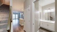 This contemporary two-floor residence offers a well-designed layout with thoughtful finishes throughout. The main living area impresses with soaring double-height ceilings and sleek hardwood-style flooring, bathed in natural light streaming through French doors that open to the outside. Transom windows above the doors further enhance the sense of openness and airiness in the space.

The kitchen is a standout feature, outfitted with crisp white shaker cabinetry, white quartz countertops, a soft green subway tile backsplash, and a full suite of stainless steel appliances including a gas range, built-in microwave, dishwasher, and French door refrigerator. A center island provides additional prep space, while pendant lighting adds a modern touch overhead.

A hallway bathroom includes a full soaking tub surrounded by clean white subway tile, finished with chrome fixtures. The bedrooms offer plush carpeting and ample closet space, with natural light provided through window blinds. Neutral tones in warm beige and soft gray flow throughout the residence, creating a cohesive and calming palette. A staircase connects the two floors, and the overall layout provides a functional, open flow ideal for comfortable everyday living.
