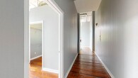 This one-bedroom, one-bathroom loft-style residence masterfully combines industrial character with contemporary finishes. Original wide-plank hardwood floors run throughout, showcasing the building's rich history beneath soaring ceilings that amplify the sense of openness. Exposed brick walls, painted in a cool grey, and visible ductwork overhead reinforce the space's authentic industrial aesthetic.

The main living area is a standout, anchored by a bank of large, multi-pane windows that frame urban skyline and treetop views while flooding the room with natural light. A ceiling fan adds comfort to this bright, airy space.

The kitchen features white shaker cabinetry, granite countertops with a subway tile backsplash, and a full suite of stainless steel appliances including a range and refrigerator. A peninsula with a corrugated metal base provides additional counter space and separates the kitchen from the living area.

The bedroom continues the loft's character with exposed brick, large windows, and the same warm hardwood flooring. A hallway with a walk-in closet connects the main living spaces. The bathroom is finished with tile flooring, a granite-topped vanity with white cabinetry, and a shower-tub combination, maintaining a clean and cohesive aesthetic throughout.