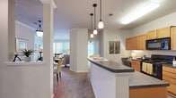 Located at 738 Elizabeth Sarah Blvd in Greer, SC, this well-appointed 3-bedroom, 2-bathroom single-floor residence offers a thoughtfully designed layout with a comfortable, functional flow throughout. The kitchen is a standout feature, outfitted with warm honey-toned cabinetry, dark countertops, black appliances including a refrigerator, range, dishwasher, and built-in microwave, and a peninsula breakfast bar illuminated by stylish pendant lighting. Wood-look flooring runs through the kitchen, creating a clean transition into the living areas. The living room is bright and welcoming, benefiting from large windows that allow generous natural light, crown molding details, and a ceiling fan. Plush carpeting adds warmth underfoot throughout the living and bedroom areas. The primary bedroom is a comfortable retreat with natural light filtering through curtained windows. Two full bathrooms are finished with wood-look flooring, warm cabinetry, and dark countertops; one features a tub-shower combination, while the other includes a standalone glass-enclosed shower. Two closets provide practical storage. Neutral wall tones and clean architectural lines give the entire space a cohesive, move-in-ready aesthetic.