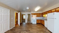 This single-floor unit is thoughtfully laid out to maximize functionality across its living spaces. The kitchen serves as a central feature, outfitted with warm honey-toned wood cabinetry providing generous upper and lower storage. White appliances, including an electric range, dishwasher, and refrigerator, complement the neutral countertops. Durable wood-look hard-surface flooring runs throughout the kitchen and main living areas, offering easy maintenance and a cohesive aesthetic.

The open-concept design connects the kitchen directly to the main living area, which is carpeted for added comfort and features a ceiling fan with a light fixture. A window allows natural light to fill the space, creating a bright, welcoming atmosphere. The textured ceilings are consistent throughout the unit, contributing to its classic residential character.

The bedrooms are carpeted with neutral-toned walls, white six-panel doors, and windows that bring in natural light, making each room feel comfortable and functional. The bathroom includes a pedestal-style sink, a mirrored medicine cabinet, and a shower with a curtain enclosure. Throughout the unit, white trim and baseboards provide clean contrast against the warm wall tones, contributing to an overall cohesive and practical living environment.