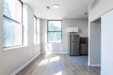 Located at 200 Godwin Ave in Paterson, NJ, this single-floor unit has been thoughtfully renovated with contemporary finishes throughout. The open living area welcomes an abundance of natural light through large windows with views of surrounding greenery, and is finished with light wood-style flooring that extends seamlessly across the main spaces.

The kitchen is well-appointed with a clean, modern design featuring two-tone cabinetry — glossy white upper cabinets paired with wood-toned lower cabinets — complemented by a tile backsplash, dark countertops, and stainless steel appliances including a refrigerator and gas range. Large-format tile flooring grounds the space and transitions neatly into the adjacent living area. A dedicated closet space adjacent to the kitchen offers convenient storage.

The bathroom showcases a striking contrast of materials, with large-format marble-look white tile flooring, bold grey stone-look wall tile, a full soaking tub and shower combination, and sleek black hardware accents that add a modern edge.

Additional rooms provide versatile, neutrally finished spaces with the same light wood-style flooring, ample natural light, and clean white walls — well-suited for bedrooms or flexible-use areas. The overall design reflects a fresh, move-in-ready aesthetic with quality finishes throughout.