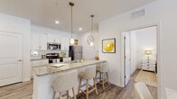 Located at 4937 Collins Rd in Jacksonville, FL, this single-floor residence offers a thoughtfully designed layout with a clean, contemporary aesthetic throughout. The kitchen serves as a central highlight, featuring crisp white cabinetry, granite countertops, stainless steel appliances including a refrigerator, range, and microwave, as well as a peninsula with bar seating illuminated by stylish pendant lighting. Wood-look flooring flows seamlessly through the main living areas, contributing to a warm and cohesive feel.

The bedrooms are bright and welcoming, each benefiting from large windows that invite generous natural light and outdoor views of surrounding greenery. The primary bedroom includes direct access to an en suite bathroom, which is outfitted with a white vanity, granite countertop, and a walk-in shower. A second bathroom mirrors the same refined finishes, offering a white vanity with granite countertop and ample storage.

Throughout the space, white walls and recessed lighting create a clean, airy atmosphere. The open-concept design connects the kitchen to the living area, making the layout feel expansive and functional. Overall, this residence combines modern finishes with a light, inviting ambiance well-suited for comfortable everyday living.