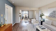 Located at 5855 Old Oak Ridge Rd in Greensboro, NC, this 2-bedroom, 2-bathroom residence offers a thoughtfully designed single-floor layout with a comfortable and cohesive aesthetic throughout. The open-concept living and dining area features hardwood-style flooring, neutral tones, and a bold steel-blue accent wall that adds character to the space. A wood-burning fireplace anchors the living room, while large windows allow natural light to fill the area. The kitchen is efficiently laid out in a U-shape with white cabinetry, light countertops, black appliances including a range and refrigerator, and a stainless steel sink beneath a window. The primary bedroom features soft carpet, a sage green accent wall, a sliding glass door opening to an outdoor balcony with greenery views, and a generous closet. The second bedroom mirrors this comfortable style with its own closet and natural light. Both bathrooms are finished with wood-style flooring, white vanity cabinetry, and shower-tub combinations. A hallway connects the bedrooms and provides access to an in-unit washer and dryer. The overall ambiance is modern yet approachable, with consistent finishes and a well-organized floor plan suitable for everyday living.