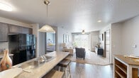 Located in Altoona, Iowa, this 2-bedroom, 2-bathroom residence offers a practical and comfortable single-floor layout designed for easy everyday living. The open-concept kitchen and living area serves as the heart of the home, where a galley-style kitchen with dark cabinetry, black stainless steel appliances, a double-basin sink, and a breakfast bar peninsula flows seamlessly into the living room. The living area is brightened by a large sliding glass door with vertical blinds that opens to an outdoor view of the surrounding greenery, complemented by a ceiling fan overhead and a textured ceiling throughout. Both bedrooms are carpeted and well-proportioned, each featuring a closet with sliding wood-panel doors and windows that bring in natural light. The primary bedroom offers a comfortable, cozy retreat. The two bathrooms are finished with tile flooring, dark vanity cabinetry, and tub-shower combinations. Additional conveniences include a dedicated pantry, in-unit laundry, and ample closet storage. Wood-look flooring runs throughout the main living areas, tying the space together with a clean, cohesive aesthetic that balances functionality with modern sensibility.