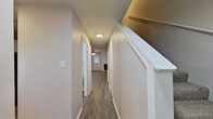 This two-story home offers a well-organized layout across two floors, providing comfortable living space for everyday needs. The main level features an open-concept living room and kitchen area with durable wood-look flooring throughout. The kitchen is equipped with white cabinetry, laminate countertops, a double-basin sink, a stainless steel electric range, a dishwasher, and a refrigerator, with a window above the sink that brings in natural light. The living area flows seamlessly from the kitchen, offering a clean, neutral palette with crisp white trim and baseboards. A hallway on the main level connects key areas of the home and features a staircase leading to the upper floor. The second floor houses the two bedrooms, including a generously sized primary bedroom complete with plush carpeting, a ceiling fan, and a private en-suite bathroom featuring a vanity with wood cabinetry and direct access to a closet. The additional bedroom is also carpeted and served by a ceiling fan. Three full bathrooms are distributed throughout the home, each featuring tub-shower combinations with clean white surrounds and chrome fixtures. Two closets provide ample storage. Neutral tones, consistent flooring choices, and functional design define the overall character of this home.