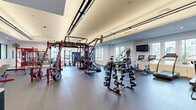 Located at 1 Haddon Blvd in Mount Laurel, NJ, this fitness center offers a generously sized, single-floor exercise space designed to accommodate a wide range of workout styles. The layout is thoughtfully organized, with distinct zones dedicated to cardio, strength training, and functional fitness.

The cardio area is lined with large windows that flood the space with natural light and provide pleasant outdoor views of the surrounding community, creating an energizing environment for treadmill and elliptical workouts. A dedicated strength zone features multi-tiered dumbbell racks stocked with a full range of free weights, adjustable benches, and Rogue-branded equipment, ideal for resistance training.

A prominent functional training section sits at the heart of the space, anchored by a large multi-station cable and power rack system in bold red, accommodating simultaneous users across various exercises. A heavy punching bag adds a combat fitness element to the mix.

The interior design features durable rubber flooring throughout, recessed and tray ceiling lighting, crisp white walls accented by a bold blue feature wall, and motivational quotes inscribed along the upper walls — including phrases like "You are stronger than you think" and "It won't challenge you, it won't change you." A wall of mirrors enhances the sense of openness. The overall ambiance is modern, clean, and purpose-built for serious fitness.