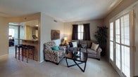 This single-story, one-bedroom, one-bathroom residence offers a practical and comfortable layout across a compact yet efficiently organized floor plan. The living room features neutral-toned carpeting, a textured ceiling, and multiple windows dressed with dark curtains and blinds that allow for flexible light control. A glass-paneled door provides direct outdoor access, enhancing the sense of openness. Adjacent to the living area, a dedicated dining space includes a ceiling fan and is visually expanded by a large wall-mounted mirror.

The kitchen is appointed with warm wood-toned cabinetry, granite-style countertops, a skylight panel for added brightness, and standard appliances including a range and refrigerator. A pass-through counter connects the kitchen to the dining area, improving flow between spaces.

The bedroom is generously sized with two closets offering ample storage, neutral carpet, and windows with exterior door access, further adding natural light. The full bathroom features a granite-style vanity countertop, an above-counter mirror, and a shower-tub combination. Throughout the unit, a consistent neutral color palette and textured ceilings contribute to a cohesive and understated residential ambiance.