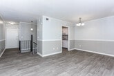 Located at 1261 Woodburn Ct in Columbus, Georgia, this two-story home offers a thoughtfully updated interior with a neutral color palette and a mix of wood-look flooring and plush carpeting throughout. The entry level opens to a well-appointed galley-style kitchen featuring white shaker cabinetry, granite countertops with a subtle speckled pattern, a stainless steel sink, and stainless appliances. Adjacent to the kitchen, a dedicated dining area is accented by a classic chandelier and connects seamlessly to the living spaces. The main living area is bright and open, with large sliding glass doors that lead to a private balcony overlooking mature trees, allowing for generous natural light. A two-toned wall treatment with chair rail molding adds architectural character throughout the main level. Upstairs, the bedrooms are carpeted and generously proportioned, each with windows fitted with blinds that provide privacy while still admitting natural light. The bathroom features a full tub-shower combination with sage green tiled surround and classic hexagonal floor tile, lending a timeless aesthetic. A staircase with a black iron railing connects the two levels, contributing to the home's clean, updated overall presentation.