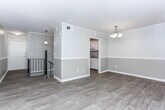 Located at 1261 Woodburn Ct in Columbus, Georgia, this two-story home offers a thoughtfully updated interior with a neutral color palette and a mix of wood-look flooring and plush carpeting throughout. The entry level opens to a well-appointed galley-style kitchen featuring white shaker cabinetry, granite countertops with a subtle speckled pattern, a stainless steel sink, and stainless appliances. Adjacent to the kitchen, a dedicated dining area is accented by a classic chandelier and connects seamlessly to the living spaces. The main living area is bright and open, with large sliding glass doors that lead to a private balcony overlooking mature trees, allowing for generous natural light. A two-toned wall treatment with chair rail molding adds architectural character throughout the main level. Upstairs, the bedrooms are carpeted and generously proportioned, each with windows fitted with blinds that provide privacy while still admitting natural light. The bathroom features a full tub-shower combination with sage green tiled surround and classic hexagonal floor tile, lending a timeless aesthetic. A staircase with a black iron railing connects the two levels, contributing to the home's clean, updated overall presentation.