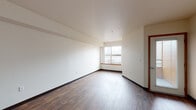 Located at 815 NW Naito Parkway in Portland's vibrant Pearl District/Old Town waterfront corridor, this single-floor unit offers a practical and well-organized layout. Rich, dark hardwood-style flooring runs consistently throughout the space, lending a cohesive and warm aesthetic to every room.

The open living area is bathed in natural light from a large window that frames views of the surrounding Portland cityscape, creating a bright and inviting atmosphere. The clean, white walls and smooth ceilings contribute to a sense of openness and simplicity throughout.

The galley-style kitchen is efficiently designed, featuring white cabinetry with wood-tone trim, ample upper and lower storage, a coil-top electric range, a full-size refrigerator, and a stainless steel single-basin sink set into a laminate countertop. A built-in range hood provides additional functionality.

A convenient closet with a hanging rod is accessible directly from the living area, offering practical built-in storage. The full bathroom includes a single-sink vanity with a laminate countertop, a full soaking tub with a shower, and continued hardwood-style flooring that maintains design consistency. The unit's straightforward floor plan and durable finishes make it a functional and comfortable space in a prime Portland location.