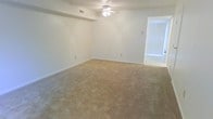This two-floor residence offers a straightforward and functional layout designed for comfortable everyday living. The interior is finished with a clean, neutral color scheme throughout, giving each space a bright and open feel.

The main living area is generously sized, featuring wall-to-wall carpeting in a warm beige tone that adds softness underfoot. A ceiling fan with an integrated light fixture is centrally mounted, providing both ventilation and ambient lighting. White walls and white baseboards keep the space feeling fresh and airy, while multiple electrical outlets are conveniently positioned throughout the room. A visible HVAC vent in the ceiling ensures year-round climate comfort.

An adjoining area, visible through a wide open doorway, is fitted with vertical blinds that allow for adjustable natural light control. The transition between spaces is open and accessible, contributing to an easy flow throughout the floor.

Spanning two floors, this residence provides the benefit of separated living and private spaces, making it well-suited for a variety of occupants. The neutral finishes and practical features throughout create a move-in-ready environment that serves as a versatile canvas for personalization.