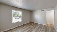 Located at 633 W Vandament Ave in Yukon, Oklahoma, this one-bedroom, two-bathroom unit offers a practical and well-appointed single-floor layout. The living room features light wood-look vinyl plank flooring, neutral warm-toned walls, and a window fitted with blinds that allows natural light to filter in with a view of the surrounding greenery. A textured ceiling carries throughout the space, adding a classic character to the interior.

The bedroom is generously sized, finished with plush carpeting, a ceiling fan with a light fixture, and a window that brings in natural light. It includes access to two closets, providing ample storage. The layout connects seamlessly to the hallway, which leads to both bathrooms. One bathroom features a vanity with granite-style countertops, gray cabinetry, and wood-look flooring, while the other includes a tiled shower-tub combination with clean white finishes.

An additional room with wood-look flooring and a ceiling fan serves as a versatile secondary space. The neutral color palette and consistent finishes throughout the unit create a cohesive and move-in-ready environment. This efficiently designed space balances comfort and functionality, making it a well-rounded option in the Yukon community.