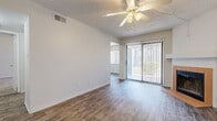 This single-floor residence offers a practical and comfortable layout with a variety of thoughtful finishes throughout. The living area is a standout space, featuring durable wood-look flooring, a ceiling fan with integrated lighting, and a sliding glass door fitted with vertical blinds that opens to an outdoor view, filling the room with natural light. A tiled fireplace with a clean white mantel adds a warm focal point to the living space, making it an inviting area for relaxation.

The kitchen is efficiently designed, featuring warm oak-toned cabinetry paired with dark speckled countertops that extend to a peninsula with an integrated sink. Appliances include a white electric range and an over-the-range microwave, providing a fully functional cooking environment. The wood-look flooring continues seamlessly through this area.

The bedrooms offer a contrast in flooring, with plush carpeting underfoot for added comfort. Each bedroom is equipped with a ceiling fan and windows with vertical blinds that allow for natural light and outdoor views. One bedroom features a closet, while the textured ceilings are consistent throughout the home, adding subtle architectural character.

Overall, the space maintains a clean, neutral palette of white walls and warm wood tones, creating a cohesive and livable environment across all rooms.