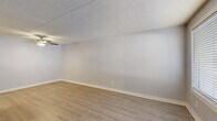 Located at 2350 E Water St in Tucson, Arizona, this single-floor residence offers a clean, neutral aesthetic throughout its well-organized layout. The living areas feature light-toned luxury vinyl plank flooring that extends through the main spaces, complemented by soft gray walls and crisp white baseboards that create a bright, airy atmosphere. Textured ceilings are found throughout the unit, adding a classic finishing touch to each room.

The kitchen is a functional highlight, equipped with ample white shaker-style cabinetry, light granite-look countertops, a stainless steel sink, and black appliances including a range with overhead ventilation and a full-size refrigerator. The layout offers generous counter and storage space, making it well-suited for everyday use.

The bedrooms are carpeted in a warm neutral tone, providing comfort underfoot, and each is fitted with a ceiling fan for year-round climate control. Windows dressed with horizontal blinds allow natural light to filter in throughout. The primary bedroom includes access to a private en-suite bathroom, a walk-in closet with built-in shelving, and features a bold dark-paneled door as a design accent.

Additional rooms offer flexible use as secondary bedrooms or office space. The overall layout, visible in the dollhouse view, is compact yet efficient, making thoughtful use of the available floor space.