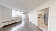 Located at 2050 Keele Street in Toronto's Mount Dennis neighbourhood, this two-bedroom, one-bathroom unit offers a well-organized layout across a single floor. The open living and dining area is a standout feature, bathed in natural light through floor-to-ceiling windows and sliding glass doors that lead to a private balcony with sweeping city views. Classic parquet hardwood flooring runs throughout the main living spaces and bedrooms, adding warmth and character to the clean, white interior.

The kitchen is thoughtfully renovated, featuring white shaker-style cabinetry, a white subway tile backsplash, dark countertops, a stainless steel sink, and a full suite of stainless steel appliances including a range, dishwasher, refrigerator, and over-the-range microwave. Light tile flooring completes the crisp, modern aesthetic of the space.

The primary bedroom benefits from large windows that frame open views and allow generous natural light, while the second bedroom includes a sliding-door closet for practical storage. Both rooms continue the parquet flooring found throughout. The bathroom is finished with white subway tile, a modern vanity with under-cabinet storage, a large mirror, and neutral tile flooring, creating a clean and functional space. The entryway is bright and welcoming, offering a smooth transition into the rest of the unit.