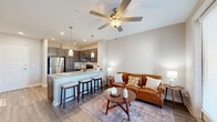 Located at 5220 Center St in Williamsburg, VA, this one-bedroom, one-bathroom residence offers a thoughtfully designed open-concept layout across a single floor. The living area is bright and welcoming, featuring large floor-to-ceiling windows and a glass-panel balcony door that fills the space with natural light and provides outdoor access. A ceiling fan adds comfort to the living room, which flows seamlessly into the kitchen.

The kitchen is well-appointed with rich dark cabinetry, granite countertops, and a full suite of stainless steel appliances including a refrigerator, range, microwave, and dishwasher. A peninsula with bar seating and pendant lighting serves as both a functional workspace and a casual dining area.

The generously sized primary bedroom features plush carpet, a ceiling fan, and a window with outdoor views. It connects directly to the full bathroom, which includes a granite vanity, tub-shower combination, and wood-look flooring. Two closets provide ample storage throughout the unit, and a dedicated laundry area adds everyday convenience.

Wood-look flooring in the main living areas and neutral wall tones throughout create a cohesive, modern aesthetic that makes this Williamsburg residence both functional and inviting.