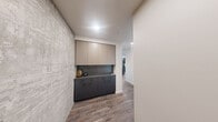 Located in the heart of Seattle's Belltown neighborhood, this contemporary two-bedroom, two-bathroom residence offers a refined urban living experience with sweeping high-rise views of Puget Sound and the city skyline. The open-concept kitchen and living area serves as the heart of the home, featuring a sleek kitchen island with stone countertops, dark cabinetry, stainless steel appliances, and pendant lighting. Wood-look flooring flows throughout, while floor-to-ceiling windows bathe the space in natural light and frame breathtaking water and cityscape views from the dining and living areas. A textured concrete accent wall adds an industrial touch to the entryway, which also features a built-in cabinetry unit with upper and lower storage. Both bedrooms are generously sized, carpeted for comfort, and offer large windows with impressive elevated city and water views. The primary bedroom includes a spacious walk-in closet with adjustable shelving systems. The primary bathroom is appointed with a long dual-sink vanity, stone countertops, matte black fixtures, large-format tile flooring, and a window overlooking the cityscape. The second bathroom features a tub-shower combination with matte black hardware and tile surround. Two dedicated closets provide ample storage throughout.