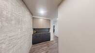 Located in the heart of Seattle's Belltown neighborhood, this contemporary two-bedroom, two-bathroom residence offers a refined urban living experience with sweeping high-rise views of Puget Sound and the city skyline. The open-concept kitchen and living area serves as the heart of the home, featuring a sleek kitchen island with stone countertops, dark cabinetry, stainless steel appliances, and pendant lighting. Wood-look flooring flows throughout, while floor-to-ceiling windows bathe the space in natural light and frame breathtaking water and cityscape views from the dining and living areas. A textured concrete accent wall adds an industrial touch to the entryway, which also features a built-in cabinetry unit with upper and lower storage. Both bedrooms are generously sized, carpeted for comfort, and offer large windows with impressive elevated city and water views. The primary bedroom includes a spacious walk-in closet with adjustable shelving systems. The primary bathroom is appointed with a long dual-sink vanity, stone countertops, matte black fixtures, large-format tile flooring, and a window overlooking the cityscape. The second bathroom features a tub-shower combination with matte black hardware and tile surround. Two dedicated closets provide ample storage throughout.