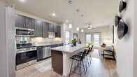 Located in San Marcos, TX, this well-appointed 2-bedroom, 2-bathroom residence offers a thoughtfully designed single-level layout. The open-concept kitchen is a standout feature, showcasing rich dark cabinetry, granite countertops, stainless steel appliances including a side-by-side refrigerator, built-in microwave, and range, as well as a central island with bar seating and pendant lighting — ideal for both cooking and casual dining. Wood-style flooring flows throughout, adding warmth and continuity to the space. The living room is bright and welcoming, highlighted by a ceiling fan, neutral walls, and French doors that open to an outdoor view of the surrounding greenery. The primary bedroom is generously sized, featuring large windows that bring in abundant natural light and offer pleasant outdoor views. Both bathrooms are finished with granite-topped dark vanities, full-width mirrors, and wood-style flooring. The primary bath includes a walk-in closet with built-in wire shelving and a soaking tub, providing a functional and comfortable retreat. The second bathroom mirrors the same refined finishes. A dedicated walk-in closet with multi-tier wire shelving adds practical storage. The overall aesthetic is clean, modern, and cohesive throughout.