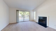 Located at 4401 Hamptonridge Drive in Charlotte, NC, this single-floor, two-bedroom, two-bathroom residence offers a well-organized layout with a comfortable sense of space throughout. The living room serves as the heart of the home, featuring plush carpeting, a classic wood-burning fireplace with a dark surround, and large sliding glass doors that open to a private balcony with tree-lined views. A second window further enhances the natural light in this room, and the vaulted ceiling adds a feeling of openness. The galley-style kitchen is thoughtfully updated with white shaker cabinetry, quartz countertops, a white subway tile backsplash, stainless steel appliances, and light hardwood-style flooring. Both bedrooms are carpeted and well-lit with windows overlooking the surrounding greenery. The spacious primary bedroom includes a dedicated closet. The bathrooms feature updated white vanities with quartz countertops, brushed nickel hardware, wood-framed mirrors, and hardwood-style flooring. A dedicated laundry room with full-size washer and dryer hookups rounds out the functional layout. Clean, neutral finishes throughout create a bright and move-in-ready atmosphere.