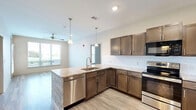 Located at 8660 N Wyandotte Street in Kansas City, MO, this thoughtfully designed 2-bedroom, 4-bathroom residence offers a comfortable and functional single-floor layout. The open-concept living and kitchen area sets the tone with light wood-style flooring, neutral walls, and ceiling fans that enhance airflow and comfort throughout. The kitchen is a standout feature, boasting rich dark wood cabinetry, granite-style countertops, a classic white subway tile backsplash, and a full suite of stainless steel appliances including a refrigerator, range, and built-in microwave. A peninsula with pendant lighting bridges the kitchen and living space seamlessly. Both bedrooms are carpeted and feature ceiling fans and windows with blinds that invite natural light and outdoor views. The primary bedroom offers a generous footprint with direct access to additional living areas. The bathrooms are finished with clean tile flooring, and at least one features a tiled walk-in shower with a built-in bench, glass sliding doors, and a rainfall showerhead. Two closets provide ample storage. The overall design palette is light, neutral, and modern, creating a clean and move-in-ready atmosphere throughout.
