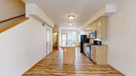 Located in Bellingham, WA, this two-story, 2-bedroom, 3-bathroom home offers a well-organized layout across two floors. The main level features an open-concept living, dining, and kitchen area united by warm light wood flooring and abundant natural light from large windows. The kitchen is equipped with light maple cabinetry, granite-style countertops, black appliances including a refrigerator, gas range, and microwave, and a central island with a built-in sink — ideal for both cooking and casual dining. A balcony off the main living area provides outdoor access, while a convenient half bathroom is also located on this floor. Carpeted stairs lead to the upper level, where both bedrooms are situated. The primary bedroom offers generous proportions, a large double-door closet, an additional walk-in closet, and an en-suite bathroom. The second bedroom is well-sized with plush carpet flooring and a bright window. A full bathroom with a tub-shower combination and tile flooring serves the upper level. With five closets total throughout the home, storage is abundant. The neutral color palette, warm wood trim accents, and consistent finishes create a cohesive and comfortable living environment throughout.