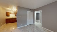 Timber Trace offers a practical and well-laid-out two-bedroom, one-bathroom single-floor residence. The open living area greets you with light-toned tile flooring, neutral gray walls, and a textured ceiling, creating a clean and versatile backdrop. A large window fitted with vertical blinds allows natural light to fill the space, and a conveniently located closet with louvered doors provides ample storage.

The kitchen is thoughtfully appointed with warm wood cabinetry, granite-style countertops, a tile backsplash, and white appliances including a coil-burner range and refrigerator. Track lighting overhead keeps the workspace bright and functional.

Both bedrooms feature plush carpeting and neutral wall tones. One bedroom offers a large window with views of surrounding greenery, bringing a sense of the outdoors inside, while the other provides a quiet, well-proportioned layout suited for comfortable living.

The bathroom includes a full-size tub and shower combination with clean white tile surround and chrome fixtures, offering a simple and functional design. Throughout the unit, consistent finishes and a neutral color palette create a cohesive and move-in-ready living environment.