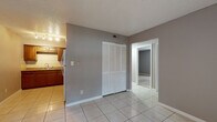 Timber Trace offers a practical and well-laid-out two-bedroom, one-bathroom single-floor residence. The open living area greets you with light-toned tile flooring, neutral gray walls, and a textured ceiling, creating a clean and versatile backdrop. A large window fitted with vertical blinds allows natural light to fill the space, and a conveniently located closet with louvered doors provides ample storage.

The kitchen is thoughtfully appointed with warm wood cabinetry, granite-style countertops, a tile backsplash, and white appliances including a coil-burner range and refrigerator. Track lighting overhead keeps the workspace bright and functional.

Both bedrooms feature plush carpeting and neutral wall tones. One bedroom offers a large window with views of surrounding greenery, bringing a sense of the outdoors inside, while the other provides a quiet, well-proportioned layout suited for comfortable living.

The bathroom includes a full-size tub and shower combination with clean white tile surround and chrome fixtures, offering a simple and functional design. Throughout the unit, consistent finishes and a neutral color palette create a cohesive and move-in-ready living environment.