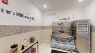 Located at Breakwater, this single-floor pet amenity space is purpose-built to make caring for your furry companions convenient and enjoyable. The room centers around a stainless steel dog wash tub, equipped with a hose and grooming attachments, and decorated with fun, pet-themed graphics that give the space a welcoming, lighthearted feel. The walls feature a two-tone finish, with white upper walls adorned with playful decals — including the charming phrase "Me Without a Dog" — and a mosaic tile wainscoting along the lower half that adds both durability and visual interest. Light-toned floor tiles keep the space bright and easy to clean. A ventilation grille ensures proper airflow throughout the room. A small utility shelf near the wash station provides convenient storage for grooming products, towels, and supplies. Recessed lighting overhead keeps the space well-lit, while the overall layout is efficient and functional. This dedicated dog wash room reflects a thoughtful approach to pet-friendly living, offering residents a clean, contained environment specifically designed for pet grooming without the mess at home.