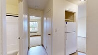 Located at 804 Cass St in La Crosse, Wisconsin, this single-floor unit features two bedrooms, one bathroom, and a compact, efficient layout. The spacious primary bedroom is the standout room, filled with natural light from two large windows that provide street-level views of the surrounding neighborhood. A baseboard heating unit and wall-mounted air conditioner ensure year-round comfort. Soft carpeting runs throughout both bedrooms and the main living area, adding warmth underfoot.

The second bedroom is a cozy, carpeted space with its own closet and a clean, neutral palette, making it versatile for various uses. The kitchen opens off the main living area and is outfitted with warm wood cabinetry featuring glass-front upper cabinets, a sink, and space for appliances including a full-size refrigerator. A built-in shelving nook near the fridge adds practical storage.

The bathroom is tiled in classic white with dark accent trim, and features a tub-shower combination with chrome fixtures and a single-sink vanity with wood cabinetry. Connecting hallways provide organized flow between the living spaces. The unit's neutral tones, functional layout, and ample natural light make it a practical and comfortable home in the heart of La Crosse.