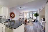 Located at 2701 Calvert St NW in Washington, DC's desirable Woodley Park neighborhood, this one-bedroom, one-bathroom residence offers a thoughtfully designed open-concept floor plan that maximizes every square foot. Light wood-tone flooring runs throughout the main living areas, lending a clean and cohesive aesthetic.

The kitchen is outfitted with white shaker cabinetry, dark granite countertops, stainless steel appliances including a full-size refrigerator and built-in microwave, and a mosaic tile backsplash that adds visual interest. A peninsula counter with seating seamlessly connects the kitchen to the dining area, where a full dining table provides comfortable everyday use.

The living room benefits from large windows that frame views of the surrounding urban streetscape, allowing generous natural light to fill the space. The bedroom is a quiet, well-appointed retreat with ample room for furnishings and access to a dedicated closet. The bathroom features light tile flooring and a clean, bright finish with a shower/tub combination.

Additional highlights include an in-unit laundry area, further enhancing the convenience of daily living. The overall ambiance is modern and understated, making it a practical and comfortable home in one of DC's most walkable and well-connected neighborhoods.