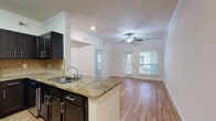 Located at 3323 McCue Rd in Houston, TX, this one-bedroom, one-bathroom residence offers a well-designed single-floor layout with a thoughtful blend of style and functionality. The open-concept kitchen and living area serves as the heart of the home, showcasing warm hardwood flooring, elegant crown molding, and ceiling fans that enhance comfort. The kitchen is outfitted with rich dark cabinetry, a granite-topped peninsula with an undermount sink, stainless steel appliances including a refrigerator and range, and a classic tile backsplash — providing ample prep and storage space. The living area receives natural light through windows with views to the outdoors, creating a bright and welcoming atmosphere. The bedroom is a comfortable retreat featuring plush carpet, a ceiling fan, and a window that brings in natural light. It connects directly to the full bathroom, which includes a vanity with a wide mirror, dark cabinetry, and a tiled shower-tub combo. A dedicated walk-in closet with wire shelving offers generous storage. Throughout the space, consistent finishes and clean architectural details contribute to a cohesive and polished interior environment.