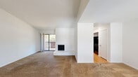 Located at 3700 Kingwood Drive in Houston, TX, this single-story residence offers a thoughtfully arranged floor plan with distinct living, kitchen, bedroom, and bathroom areas. The living room serves as the heart of the space, highlighted by soaring vaulted ceilings, neutral carpet flooring, and a striking white-paneled fireplace with a chevron-patterned surround and raised hearth. A full-width sliding glass door bathes the room in natural light and opens to a private balcony overlooking lush greenery, creating a seamless indoor-outdoor connection.

The galley-style kitchen is well-appointed with rich dark cabinetry, granite countertops, a stainless steel sink, and black appliances. Light hardwood-style flooring runs throughout this area, complementing the warm tones of the cabinetry. An adjacent utility nook adds practical functionality to the layout.

The bedroom is carpeted and comfortably sized, featuring a ceiling fan and access to a walk-in closet. The bathrooms are appointed with marble-style wall surrounds on the tub and shower enclosures, paired with wood-tone flooring and clean, bright white finishes throughout, contributing to a polished and cohesive aesthetic.