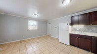 Located in North Chesterfield, VA, this efficient one-bedroom, one-bathroom residence offers a well-organized single-floor layout designed to maximize every square foot. Light-toned ceramic tile flooring runs consistently throughout the entire space, creating a clean, cohesive look.

The combined kitchen and living area serves as the heart of the home. The kitchen is outfitted with rich dark-brown cabinetry, a tile backsplash, light countertops, and white appliances including a refrigerator and range. A stacked washer and dryer unit is conveniently integrated into the kitchen area. The open living space adjoins the kitchen, featuring soft gray walls, crown molding, and a window that brings in natural light.

The bedroom is a well-proportioned retreat with the same tile flooring, crown molding, gray walls, and a window providing natural light and outdoor views. A closet offers dedicated storage, keeping the space organized and functional.

The bathroom is clean and bright, featuring a white vanity with ample counter space, a toilet, and tile flooring consistent with the rest of the home. Chrome fixtures and white walls contribute to a crisp, tidy atmosphere.

Crown molding details carried throughout the space add a thoughtful architectural touch, elevating the overall character of this practical and move-in-ready residence.