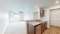 Located at 1211 Enterprise Dr E in Belle Plaine, Minnesota, this one-bedroom, one-bathroom unit offers a thoughtfully designed single-floor layout. The open-concept living and kitchen area serves as the heart of the space, with the kitchen featuring rich dark wood cabinetry, granite-look countertops, a peninsula with a double sink, stainless steel appliances including a refrigerator, electric range with microwave above, and a dishwasher. Light hardwood-style flooring runs through the kitchen, which also benefits from a dedicated pantry closet for additional storage. The kitchen flows seamlessly into the carpeted living room, which is bathed in natural light from multiple windows and finished with a ceiling fan with light fixture. The spacious bedroom offers plush carpeting, a large window with outdoor views, and ample room for furnishings. Two closets provide generous storage throughout the unit. The bathroom is clean and functional, featuring a full tub and shower combination with a curved curtain rod and hardwood-style flooring. An in-unit laundry area adds everyday convenience. Neutral tones and clean finishes throughout create a bright, welcoming atmosphere.