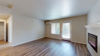 Located at 16610 NE Halsey St in Gresham, Oregon, this single-story space offers a thoughtfully designed layout with a clean, modern aesthetic throughout. The main living area features smooth hardwood-style flooring that reflects natural light streaming in through a large window and glass door, which also provides outdoor access and views of surrounding greenery. A wall-mounted mini-split system provides efficient climate control, while a sleek electric fireplace with a contemporary surround adds a striking focal point to the living space.

The kitchen is well-appointed with rich, dark wood cabinetry extending to the ceiling for ample storage, light-toned countertops, and a full suite of stainless steel appliances including a range, microwave, dishwasher, and refrigerator. A kitchen island offers additional prep and seating space, and pendant lighting adds a refined touch overhead.

The bedroom is finished with plush wall-to-wall carpeting and a window overlooking lush trees, creating a quiet, comfortable retreat. The bathroom features wood-style flooring, a dark wood vanity with an integrated sink, a large mirror, and grab bars, combining functionality with a polished appearance throughout.