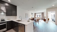 Located at 585 North Ave in New Rochelle, NY, this thoughtfully designed single-floor residence combines modern aesthetics with functional living. The open-concept layout seamlessly connects the kitchen, dining, and living areas, creating a bright and cohesive space bathed in natural light from large black-framed windows.

The kitchen is a standout feature, equipped with dark shaker-style cabinetry, quartz countertops, a subway tile backsplash, stainless steel appliances including a range with a wall-mounted hood, and a peninsula with bar seating — ideal for casual dining or entertaining. Adjacent to the kitchen, the dining area offers dedicated space for a full dining set, complemented by warm wood tones and curated wall art.

The living room is welcoming and light-filled, with large windows framing outdoor views and light wood-look flooring that flows throughout the unit. The bedrooms are well-appointed, one featuring elegant wainscoting paneling and a walk-in closet, while another benefits from generous window exposure. The bathroom is finished with large-format floor tiles, a glass-enclosed walk-in shower with mosaic tile flooring, and a backlit vanity mirror. Clean white panel doors with matte black hardware add a refined, contemporary touch throughout.