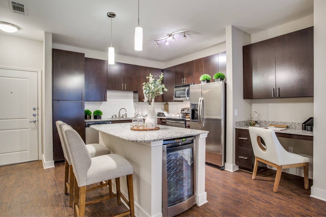 Kitchen with island, granite countertops, dark wood cabinetry, and stainless steel appliances - Park Central at Flower Mound