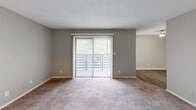 Located in Birmingham, AL, this two-bedroom, one-bathroom residence offers a well-organized single-floor layout designed for comfortable everyday living. The living area is carpeted and bathed in natural light through a large sliding glass door fitted with vertical blinds, providing a direct connection to the outdoors. Neutral gray walls and a textured ceiling carry throughout the space, creating a consistent and clean aesthetic. The entryway opens directly into the living area, which also connects seamlessly to the kitchen. The kitchen is outfitted with white cabinetry, dark granite-style countertops, a stainless steel sink, and black appliances including a refrigerator and dishwasher, all set over wood-look vinyl flooring. The generously sized primary bedroom features wall-to-wall carpet, gray walls, and direct views into both the bathroom and a dedicated closet. The second bedroom is equally well-proportioned with the same neutral finishes and plush carpeting. The bathroom includes a combination tub and shower, a toilet, and wood-look flooring, with a textured wall finish adding subtle dimension. A closet provides additional storage within the unit. The overall ambiance is clean, neutral, and move-in ready.
