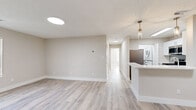 This single-floor residence in Manchester, CT offers a clean, contemporary interior defined by light-toned luxury vinyl plank flooring, neutral beige walls, and white trim throughout. The open-concept living area flows seamlessly from the main living space toward the kitchen, creating a bright and functional layout. Flush-mount and pendant lighting fixtures complement the textured ceilings, while a sliding glass door with vertical blinds connects the living area to a private outdoor space, allowing natural light to fill the room from multiple angles.

The kitchen is well-appointed with white shaker-style cabinetry, white quartz countertops, a grey subway tile backsplash, and stainless steel appliances including a gas range with over-the-range microwave. A peninsula provides additional prep and serving space.

The bedrooms are generously proportioned, featuring large windows with blinds and closets with built-in shelving. A dedicated laundry area houses a stacked washer and dryer unit alongside a water heater.

The bathroom features marble-look tile extending from floor to tub surround, grey slate-style floor tile, a white vanity, and a full tub-shower combination, delivering a polished, cohesive aesthetic throughout.